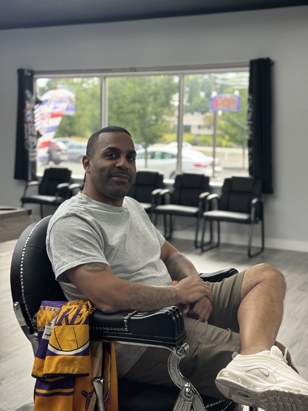 Larry seated in his barber chair by the shop window